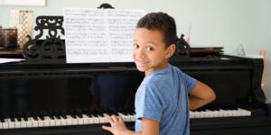 The image depicts a boy engrossed in his piano lesson in Hurstville, Sydney, Australia. Seated at the piano, his fingers delicately touch the keys as he concentrates on playing a musical piece. The room is filled with the warm glow of natural light, enhancing the serene atmosphere. The boy's focused expression and posture reflect his dedication and eagerness to learn. The image captures a moment of musical education and growth as the boy immerses himself in the joy of playing the piano in Hurstville, Sydney, Australia