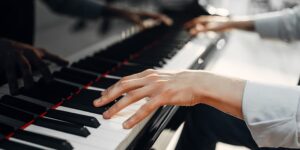 teacher singing lessons – vocal lessons, singing classes – vocal classes, singing coach – vocal coach, In a classroom in Hurstville, Sydney, Australia, a young boy's hands gracefully glide across the keys of a piano, showcasing his accomplishments from his piano lessons. The focus is solely on his hands and the piano, capturing the moment of musical expression. The boy's fingers display skillful dexterity and control as they produce beautiful melodies. The classroom environment is visible in the background, providing a backdrop to the intimate scene. The image portrays the young boy's dedication and progress in his piano learning journey.